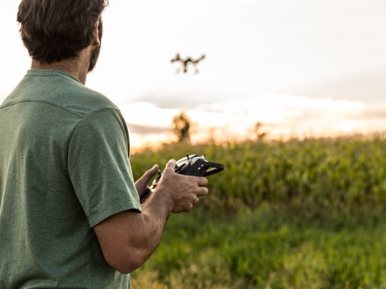 Autonomous & Uncrewed Vehicle Systems image, man flying a drone in a meadow at sunset