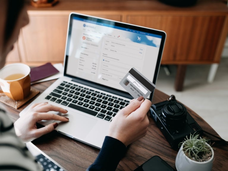 Personal in front of laptop holding up a credit card