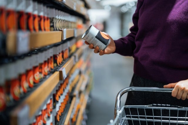 person holding canned good in a grocery store