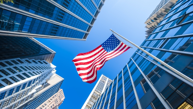 American flag between a city block of tall buildings