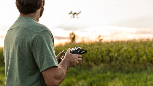 Autonomous & Uncrewed Vehicle Systems image, man flying a drone in a meadow at sunset