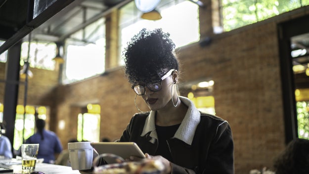 Businesswoman working inside a restaurant, using digital tablet